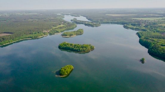 Jezioro z wyspami pokrytymi zielonym lasem, widok z drona