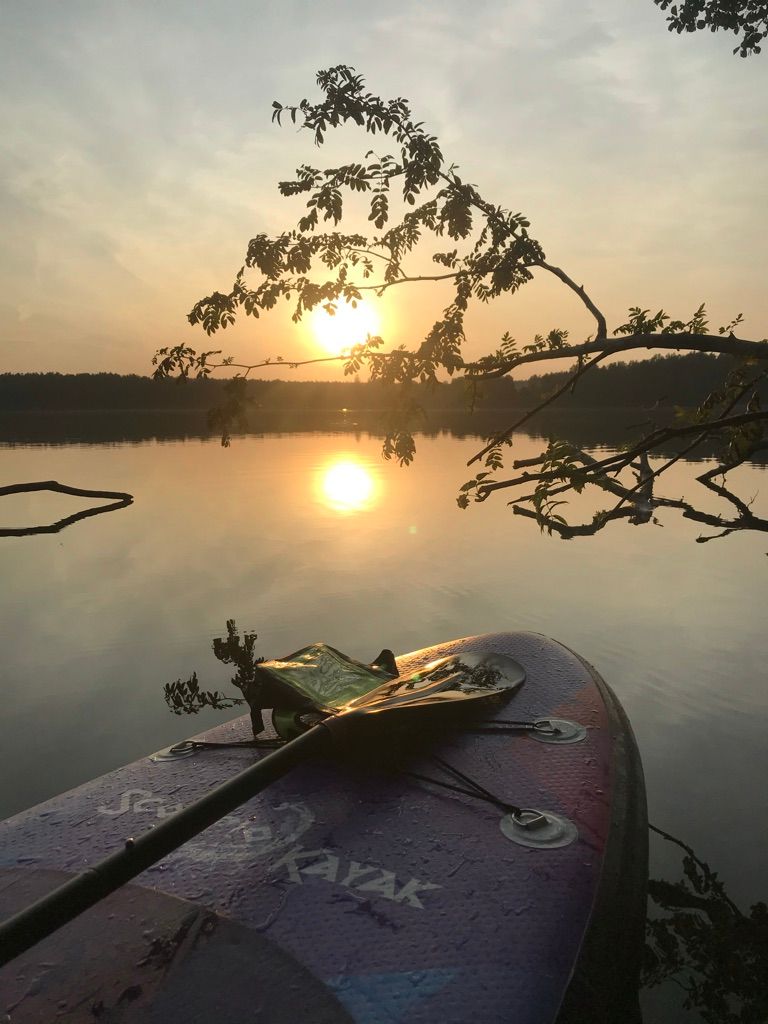 Paddleboard z wiosłem o zachodzie słońca na jeziorze