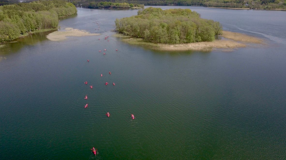 Grupa kajakarzy w czerwonych kajakach na jeziorze, widok z drona